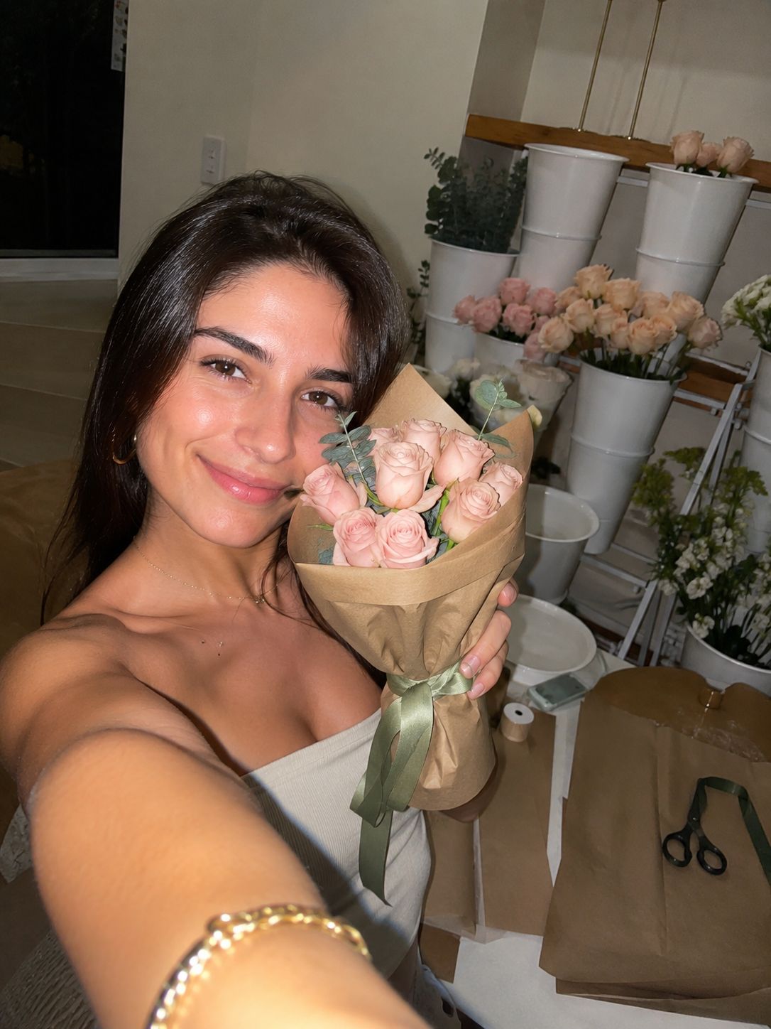 A guest photographing her blush rose bouquet beside the flower station after an event